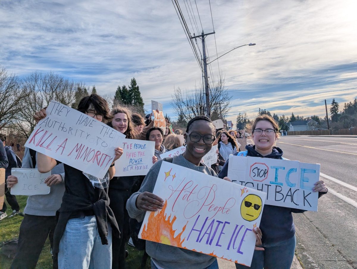 Students during the walkout hold up signs they made along Boones Ferry Road as they protest ICE’s continued activity.