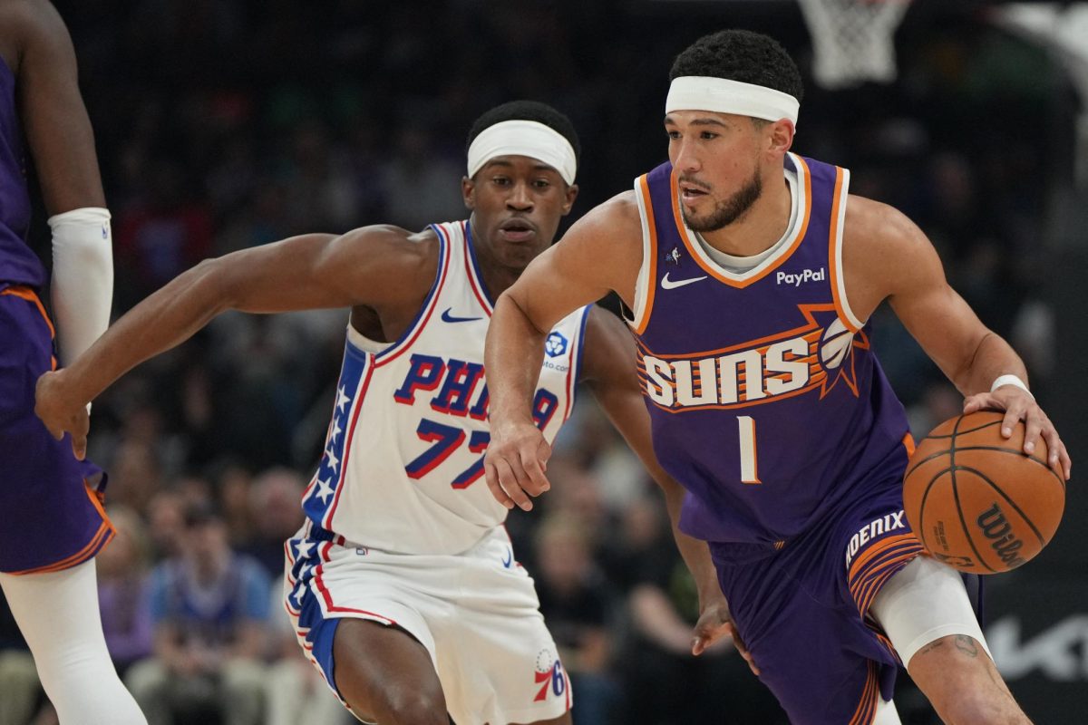 Phoenix, Arizona, USA; Phoenix Suns guard Devin Booker (1) drives around Philadelphia 76ers guard Vj Edgecombe (77) during the first half of an NBA game at Mortgage Matchup Center.